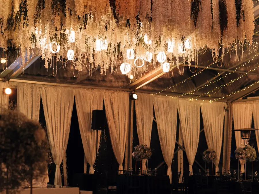 Massive square floral chandelier installation suspended over a black dance floor with a custom gold monogram decal.