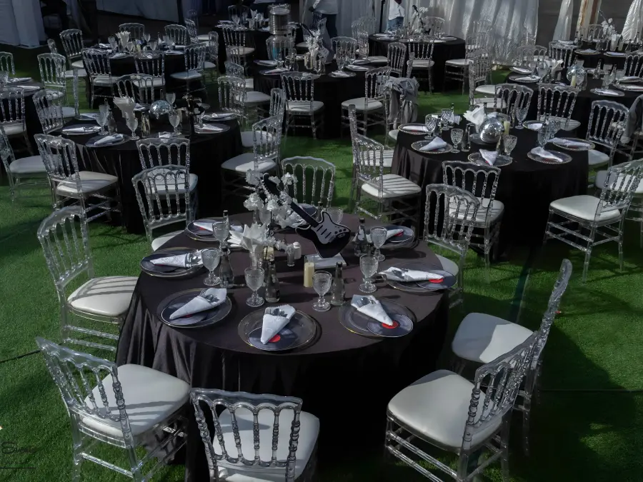High-angle shot of a music-themed event layout with vinyl record chargers, guitar centerpieces, and silver Chiavari chairs.