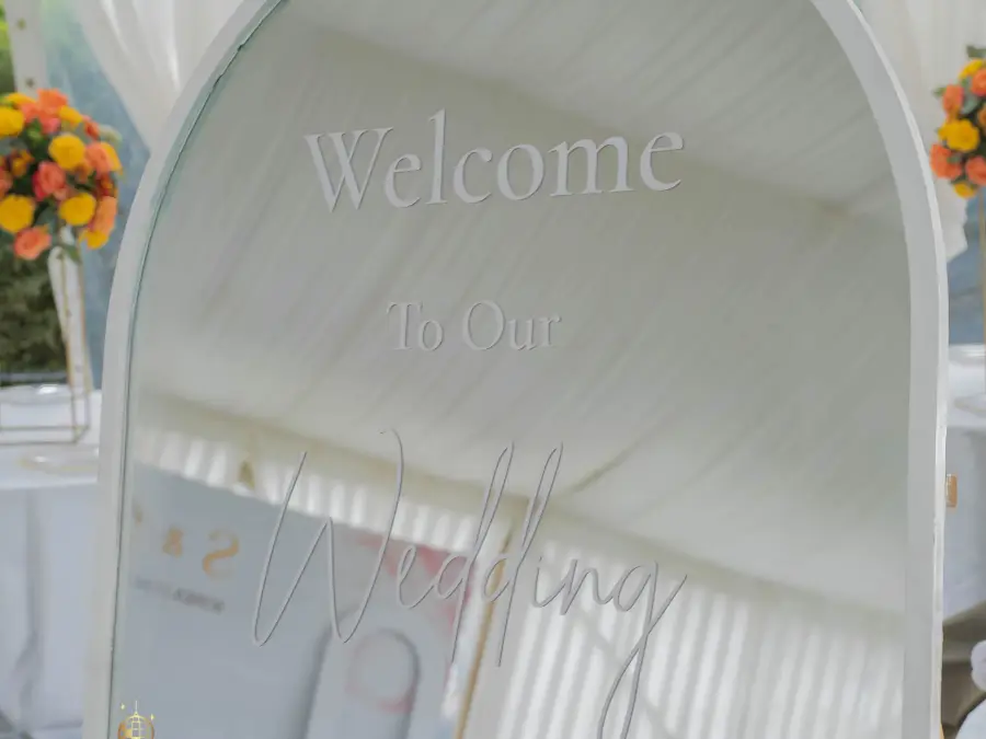 White arched floor mirror with vinyl lettering "Welcome To Our Wedding" used as an elegant welcome sign.