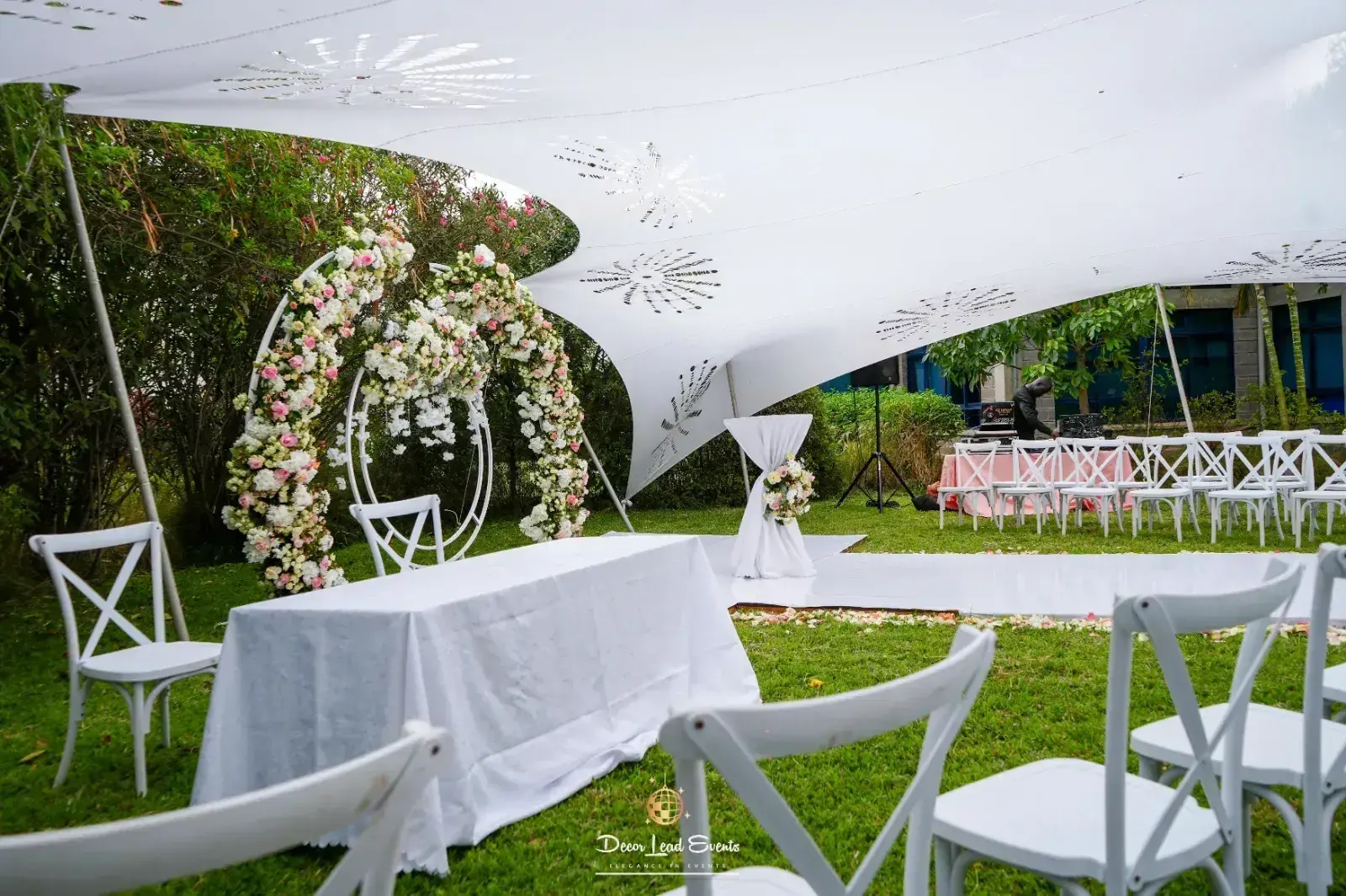 Garden wedding ceremony under a white canopy with floral arch