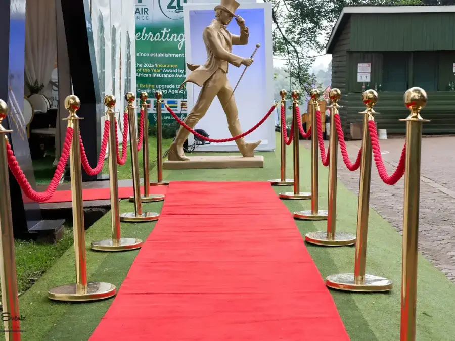 Red carpet entrance lined with gold stanchions and red velvet ropes, leading to a gold statue and