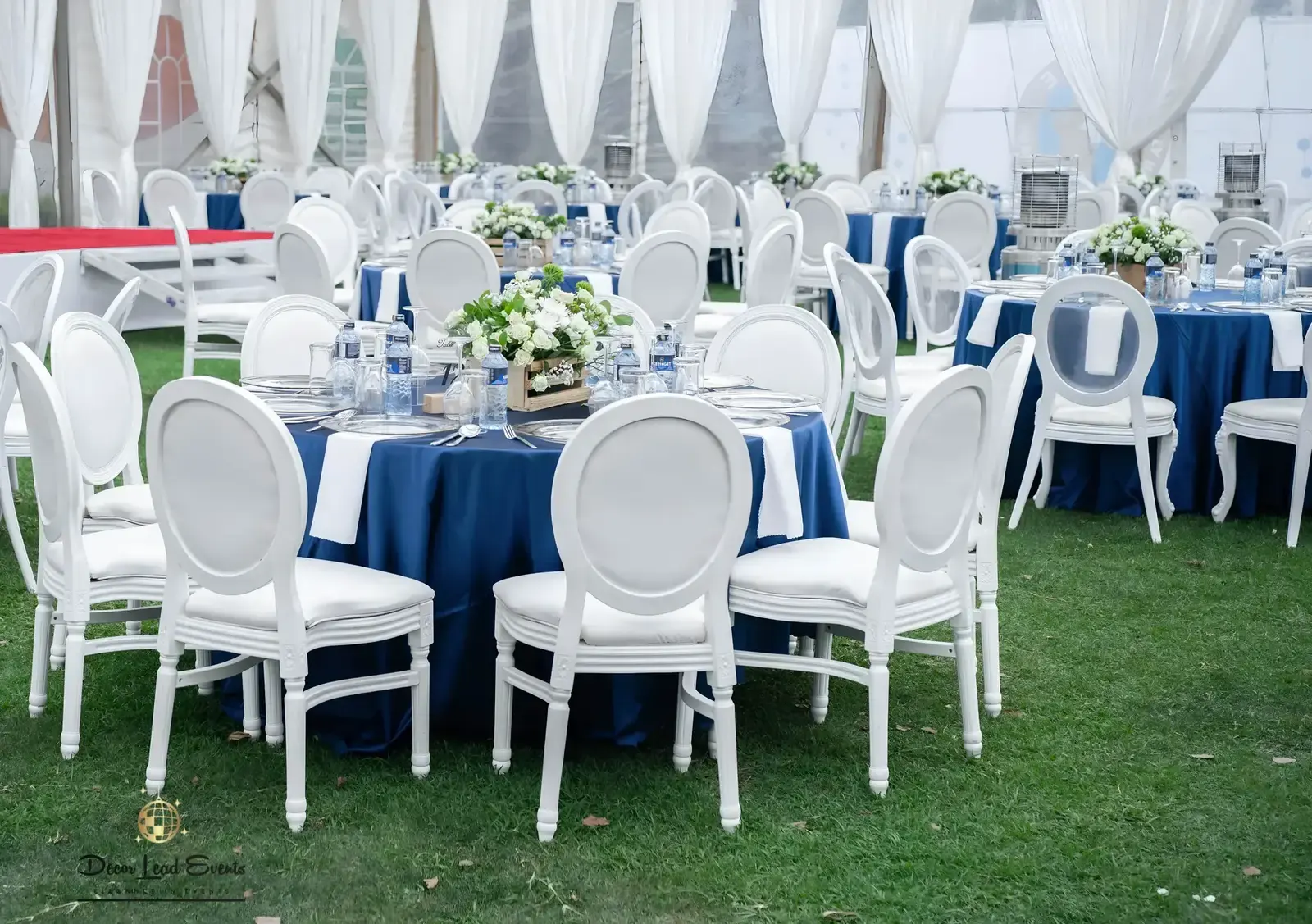 Blue table settings inside a white tent with round seating